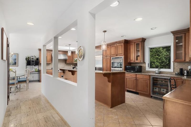 Kitchen featuring stainless steel appliances, decorative backsplash, beverage cooler, extractor fan, and recessed lighting