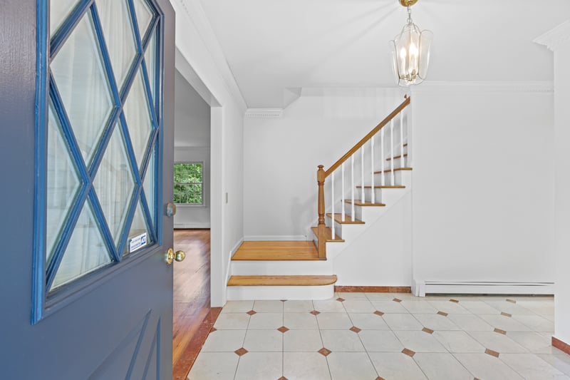Tiled entryway, with ornamental molding, stairs, and a chandelier