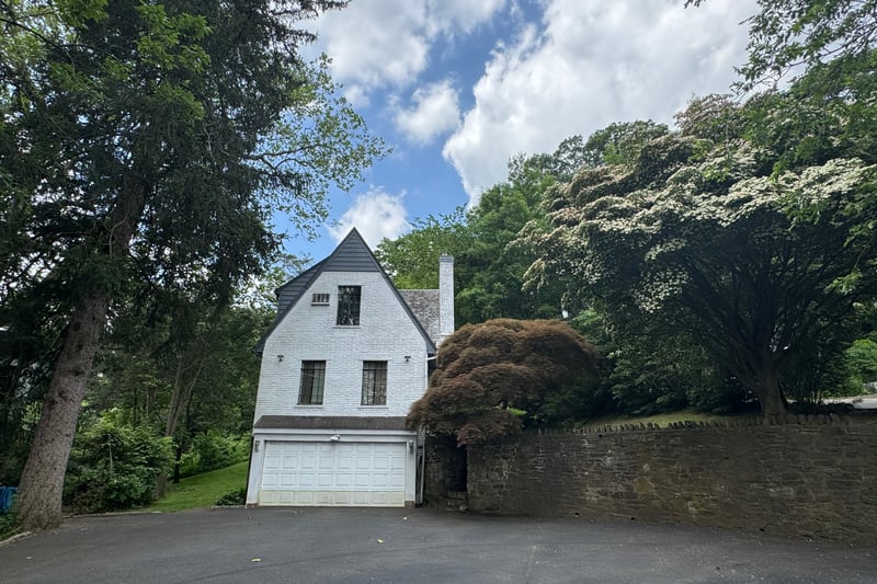 View of property exterior featuring driveway, an attached garage, and a chimney