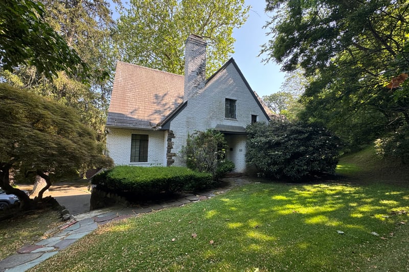 Tudor home with brick siding, a front lawn, and a chimney