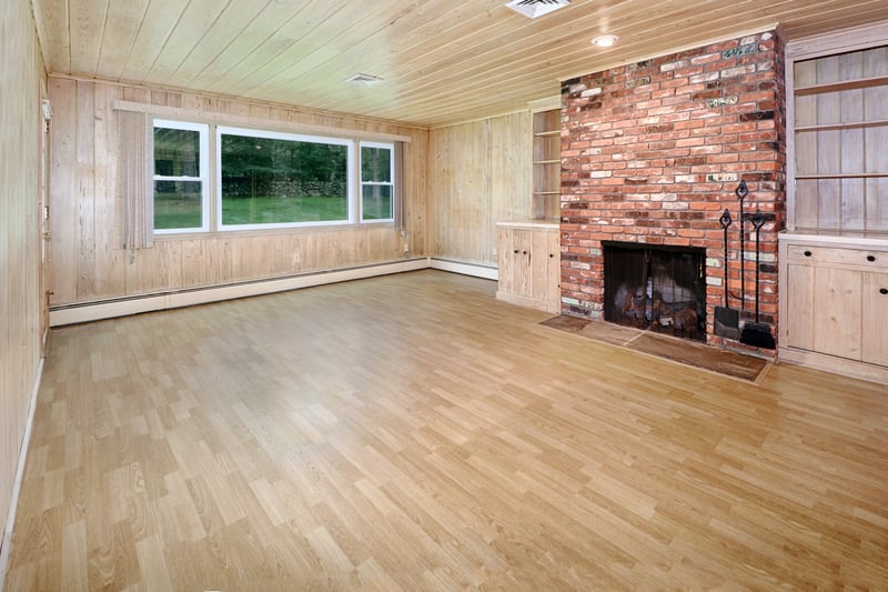 Wood paneled family room with access to backyard features gas fireplace with brick surround.