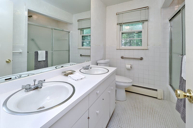 Hall bath on upper level contains vanity with double sinks and a tub with shower and tile floor.