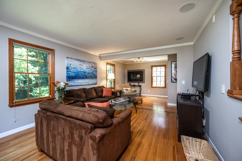 Living room featuring hardwood flooring, crown molding and views of nature.