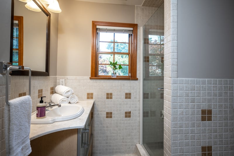 Hall bathroom featuring vanity, tile walls, and shower.