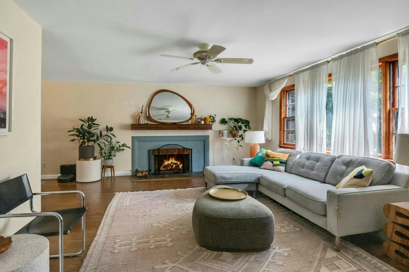 Living area featuring wood finished floors, ceiling fan, and a brick fireplace