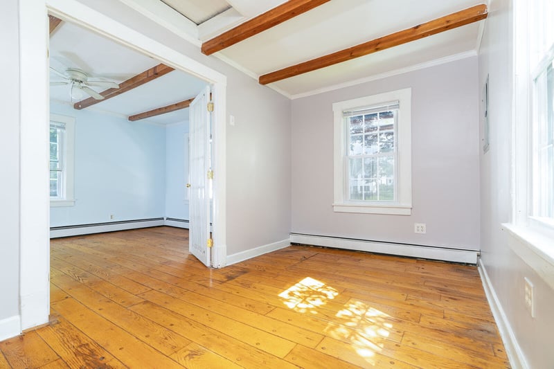 Empty room with beam ceiling, light wood finished floors, a baseboard radiator, a ceiling fan, and crown molding
