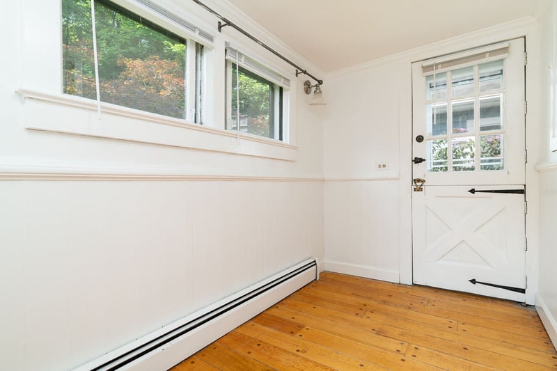 Doorway to outside featuring a baseboard radiator, ornamental molding, light wood-style flooring, and a wainscoted wall