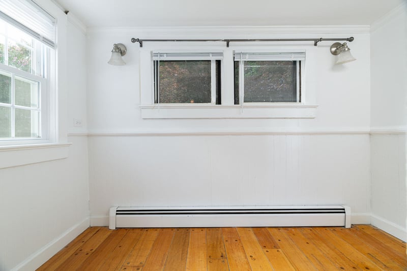 Spare room featuring a baseboard radiator, wood-type flooring, a wainscoted wall, and crown molding