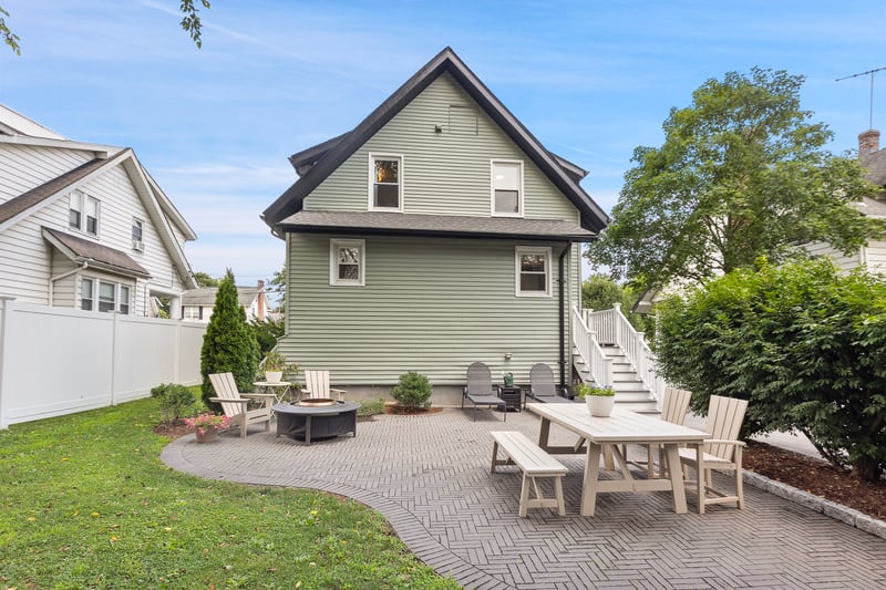 Rear view of house featuring a fire pit, a patio, stairway, and roof with shingles...