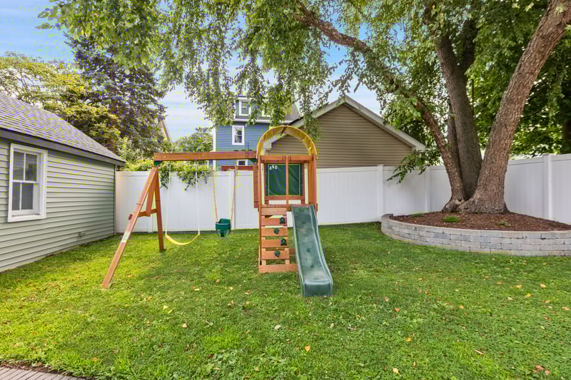 View of front of house with a playground and a fenced backyard...