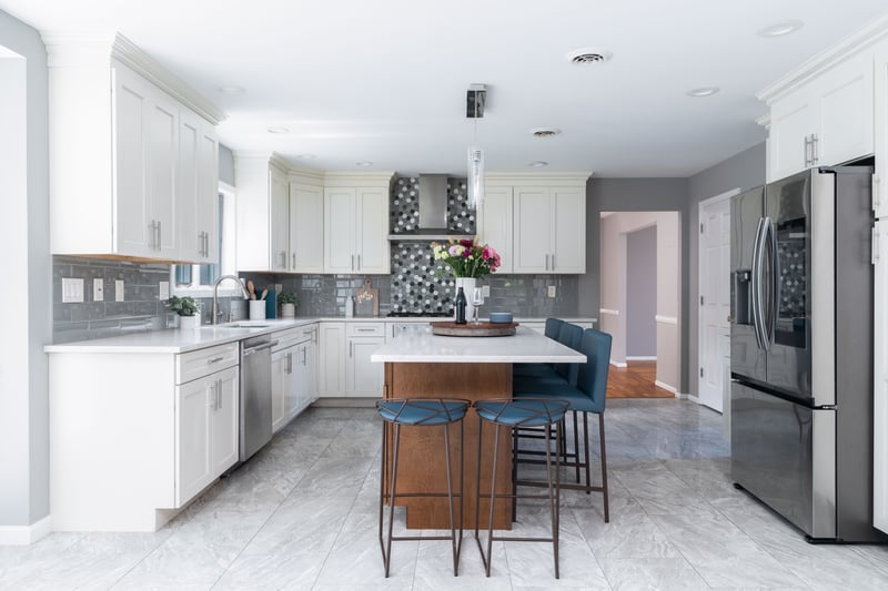 Kitchen featuring stainless steel appliances, light countertops, a kitchen island, wall chimney range hood, and decorative backsplash