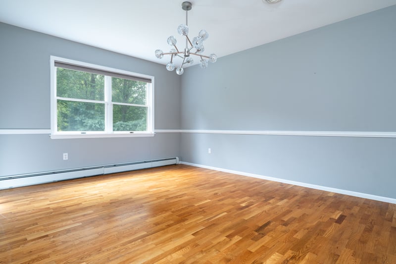 Unfurnished living room with baseboard heating, light wood-type flooring, a ceiling fan, and high vaulted ceiling