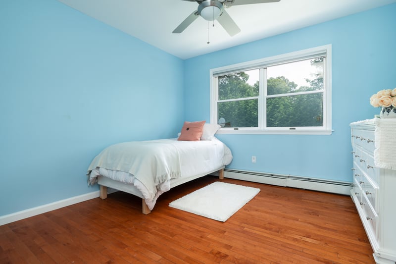 Bedroom featuring a baseboard heating unit, wood-type flooring, and ceiling fan