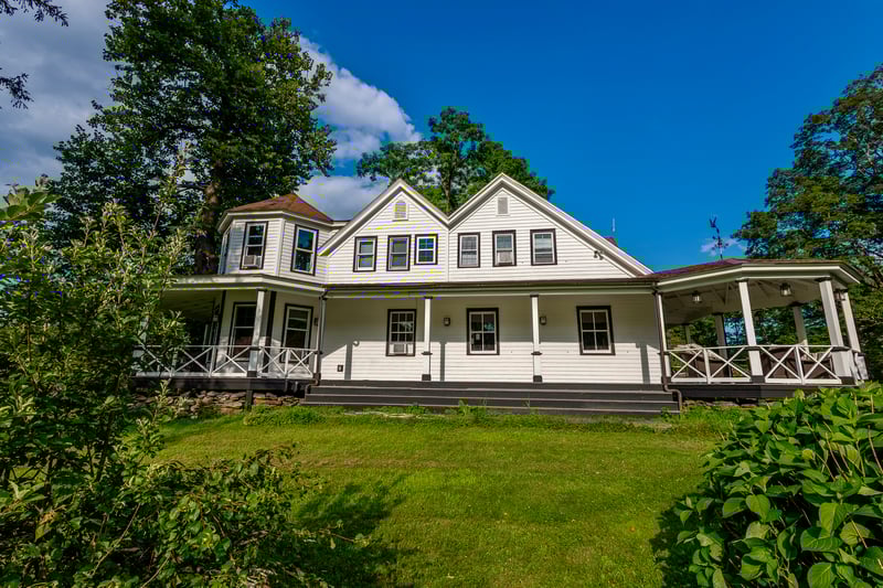 Rear view of property featuring a yard and covered porch