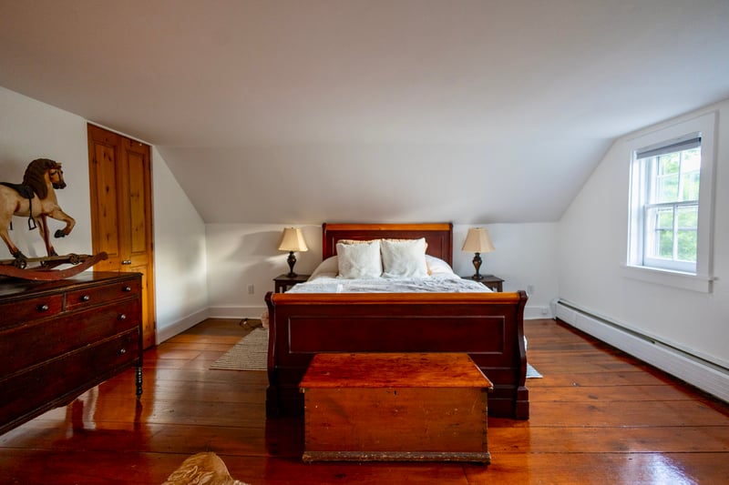 Bedroom featuring hardwood / wood-style floors, lofted ceiling, and a baseboard heating unit