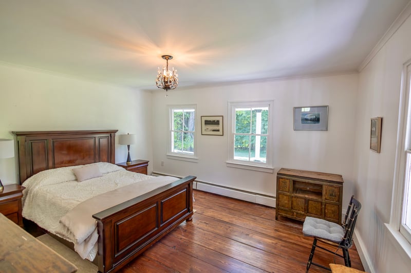 Bedroom with dark wood-style floors, baseboard heating, a chandelier, and ornamental molding
