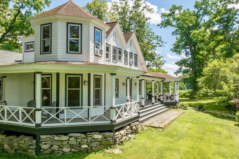 View of property exterior featuring roof with shingles, a porch, and a lawn