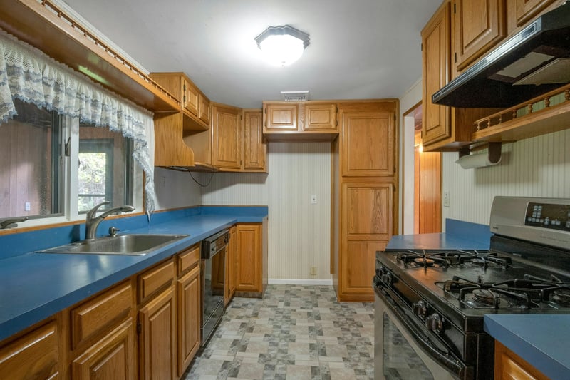 Kitchen featuring stainless steel gas range, range hood, brown cabinetry, and dishwasher...