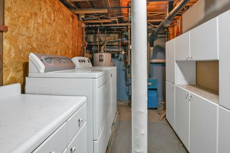Laundry room featuring cabinet space, washing machine and clothes dryer, and water heater...