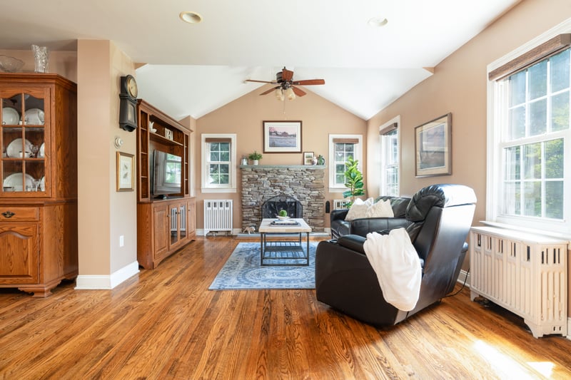 Living area with radiator heating unit, vaulted ceiling, light wood-style flooring, a fireplace, and recessed lighting