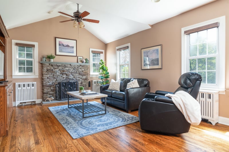 Living room featuring radiator, lofted ceiling, wood finished floors, ceiling fan, and a fireplace