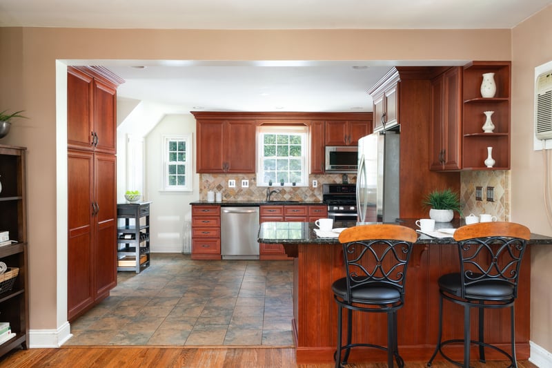 Kitchen with a peninsula, stainless steel appliances, a breakfast bar area, tasteful backsplash, and dark wood-style flooring