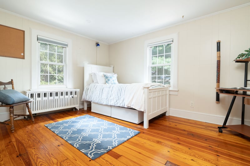 Bedroom with radiator heating unit, ornamental molding, wood-type flooring, and wood walls