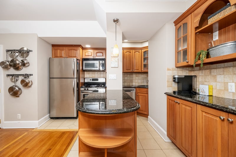 Kitchen with open shelves, appliances including dishwasher stainless steel finishes, light tile patterned flooring, dark stone countertops, and recessed lighting 