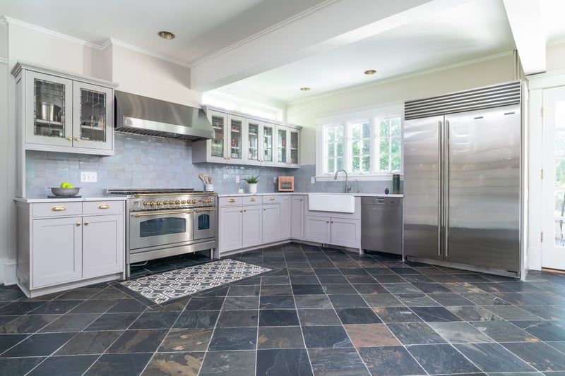 Kitchen featuring crown molding, premium appliances, wall chimney range hood, backsplash, and glass insert cabinets