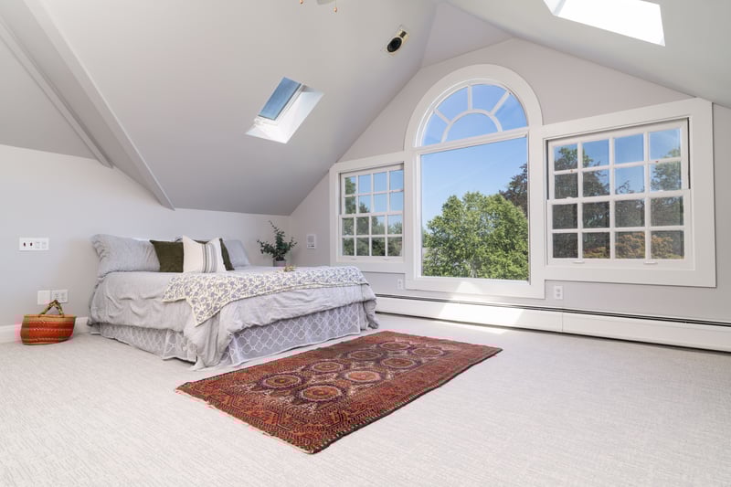 Bedroom with a skylight, lofted ceiling, a baseboard heating unit, and carpet floors