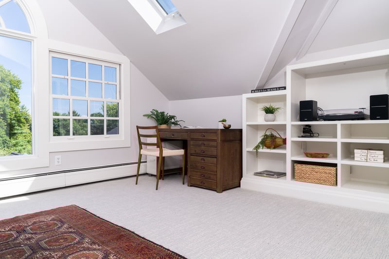 Home office with a skylight, lofted ceiling, light colored carpet, and baseboard heating