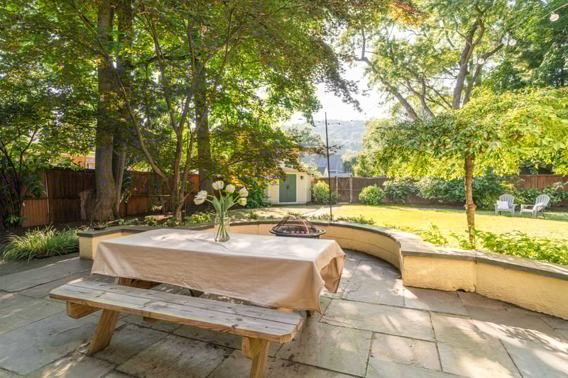 Fenced backyard with a patio area, an outbuilding, a fire pit, and outdoor dining area