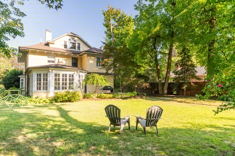 Back of house featuring a chimney, stucco siding, and a sunroom