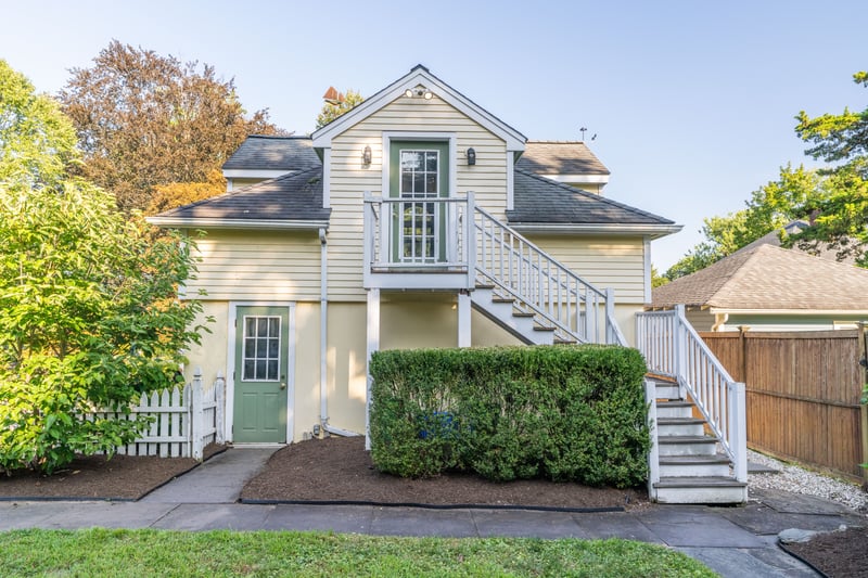 View of front of property with stairway, a shingled roof, and stucco siding