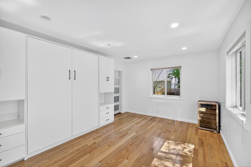 Primary Bedroom with Murphy bed or can be closed and used as a wall, stackable washer and clothes dryer in separate laundry room as seen light wood-type flooring, and recessed lighting