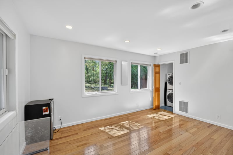 Primary Bedroom with Murphy bed or can be closed and used as a wall, stackable washer and clothes dryer in separate laundry room as seen light wood-type flooring, and recessed lighting