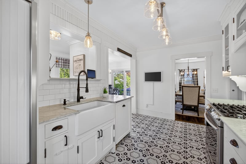 Kitchen with white cabinetry, pendant lighting, ornamental molding, glass insert cabinets, and marble countertops