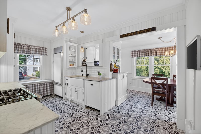 Kitchen with white cabinets, Sub-Zero fridge, decorative light fixtures, natural light, and ornamental molding