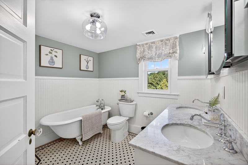 Full bathroom featuring a freestanding tub, a wainscoted wall, and double vanity plus a stall shower.