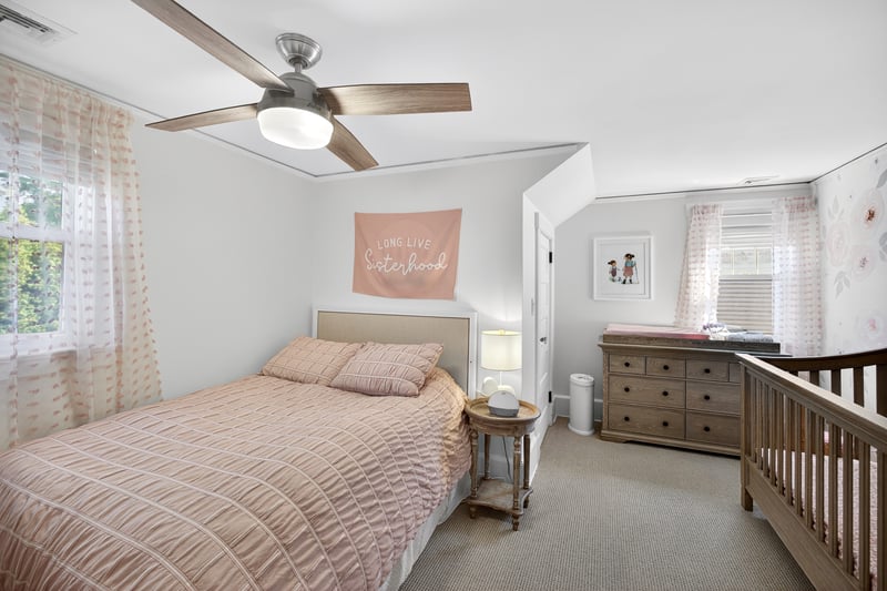 Bedroom #1 featuring light colored carpet, a nursery area, ceiling fan, and crown molding
