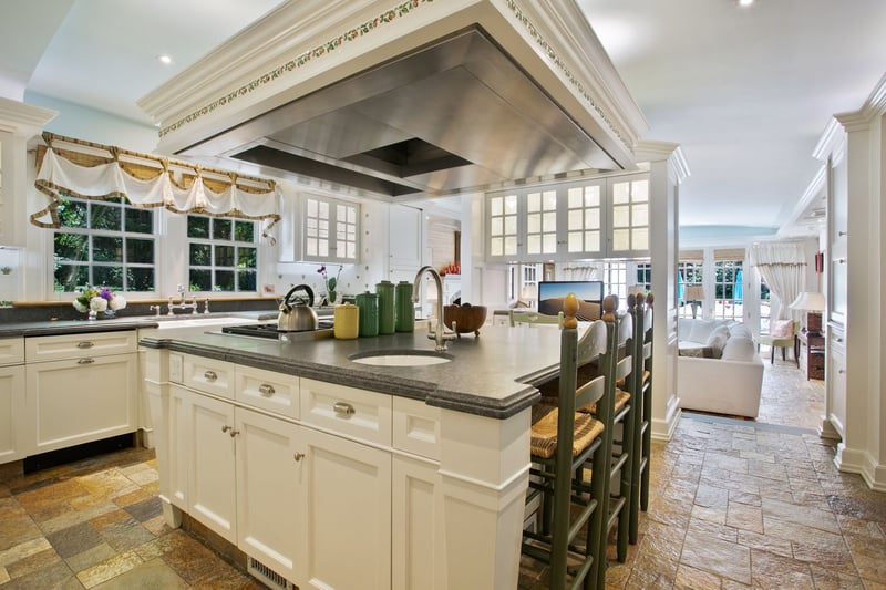 large island with industrial hood and Wolf Range with seating and additional sink.