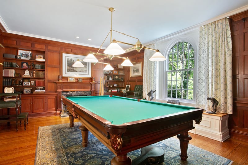 Relax and play some pool in your Billard room with custom wood paneling, built in pool rack, and marble wood-burning fireplace.