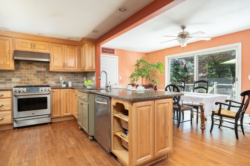 Kitchen with stainless steel appliances, granite countertops, a peninsula, backsplash, and under cabinet range hood
