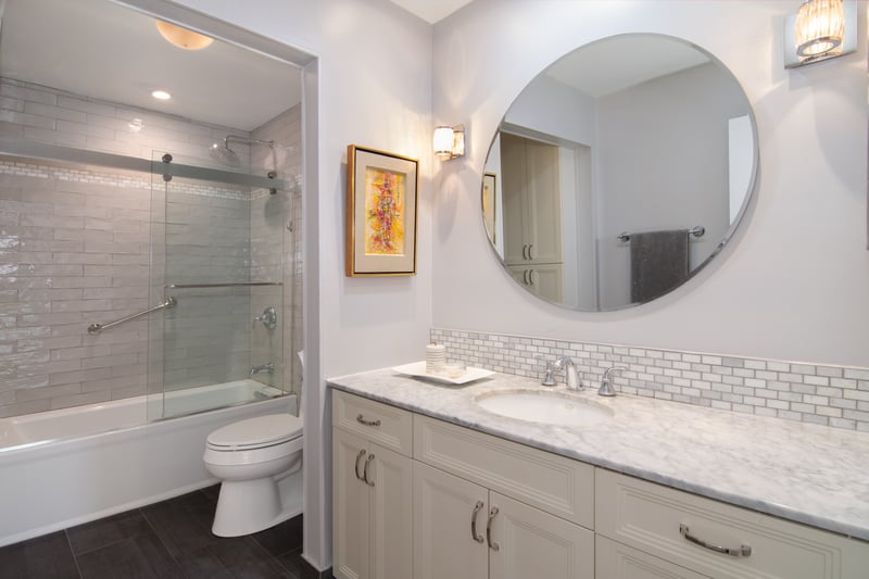 Bathroom featuring enclosed tub / shower combo, vanity, backsplash, and recessed lighting....