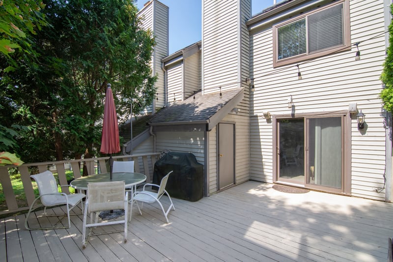 Wooden terrace with outdoor dining space and a grill....