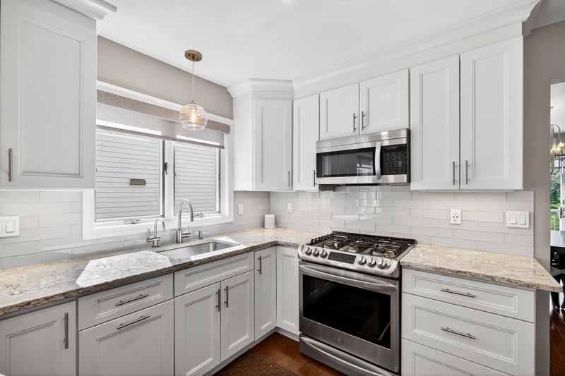 Kitchen with healthy amount of natural light, appliances with stainless steel finishes, and light quartzite counters