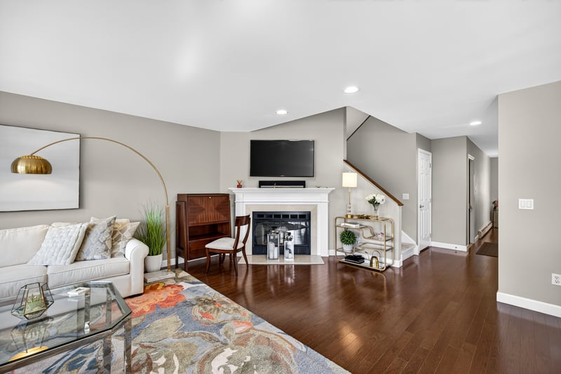 Alternate view of Living room with dark wood floors, and fireplace with flush hearth, recessed lighting, and stairway to the bedrooms.
