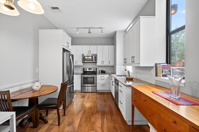 Large Updated Kitchen featuring appliances with stainless steel finishes, backsplash, dark wood-style floors, white cabinets, and light stone countertops...