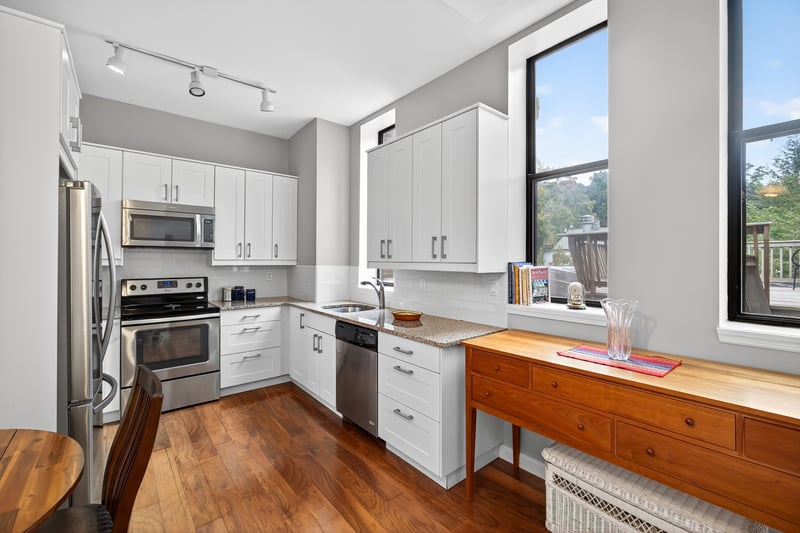 Large Updated Kitchen with stainless steel appliances, white cabinets, dark wood-type flooring, decorative backsplash, and light stone counters...