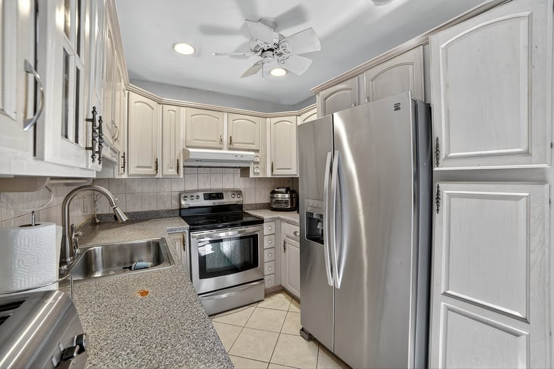 Kitchen featuring stainless steel appliances, light tile patterned floors, recessed lighting, decorative backsplash, and under cabinet range hood